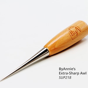 May include: ByAnnie's Extra-Sharp Awl with a wooden handle and a silver metal tip. The handle is light brown with the ByAnnie's logo etched into the wood. The awl is designed for detailed crafting and sewing projects.
