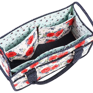 May include: A blue and white floral fabric tote bag with multiple compartments and a zipped closure. The bag has two navy blue handles.