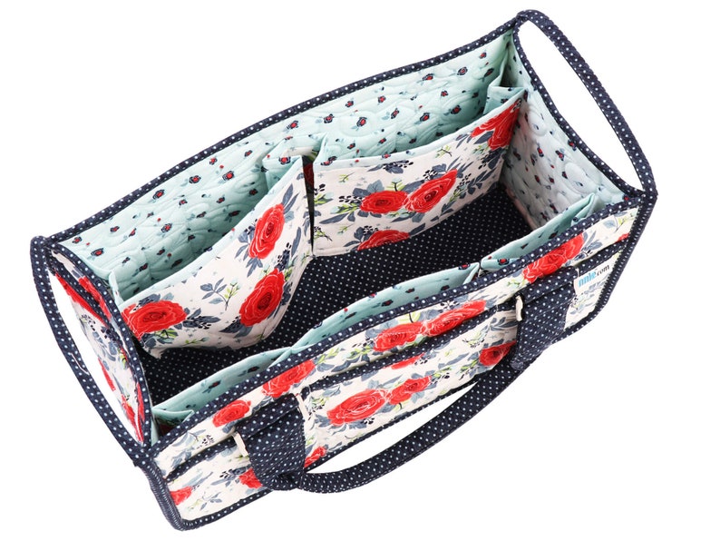 May include: A blue and white floral fabric tote bag with multiple compartments and a zipped closure. The bag has two navy blue handles.