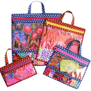 Puede incluir: Cuatro bolsas con cremallera con paneles de vinilo transparentes y dise&ntilde;os de tela floral de colores. Las bolsas est&aacute;n hechas de tela azul con lunares blancos y tienen cremalleras rosas. Las bolsas tienen asas y est&aacute;n anidadas unas dentro de otras.
