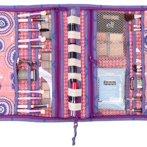 May include: Purple and pink zippered makeup bag with multiple compartments and elastic loops for holding brushes, palettes, and other makeup items. The bag is open and shows the contents, including brushes, eyeshadow palettes, and a small bottle of lotion.