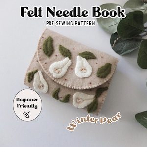 Op de afbeelding: Een beige vilten naaldenboek met een klepsluiting, versierd met witte peer- en groene bladtoepassingen. De tekst "Felt Needle Book PDF Sewing Pattern" staat bovenaan. De woorden "Beginner Friendly" en "Winter Pears" zijn ook zichtbaar.