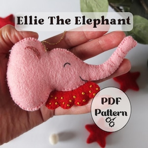 Puede incluir: Un adorno de elefante de fieltro rosa con ojo y boca bordados, que lleva un cuello con volantes rojo con puntos amarillos. El texto Ellie The Elephant aparece en la parte superior y una insignia circular con PDF Pattern es visible en la esquina.