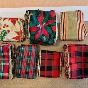 May include: Assortment of Christmas ribbon with gold trim. The ribbons feature plaid patterns in red, green, and black, a floral pattern with red poinsettias, and a gold and red striped pattern.