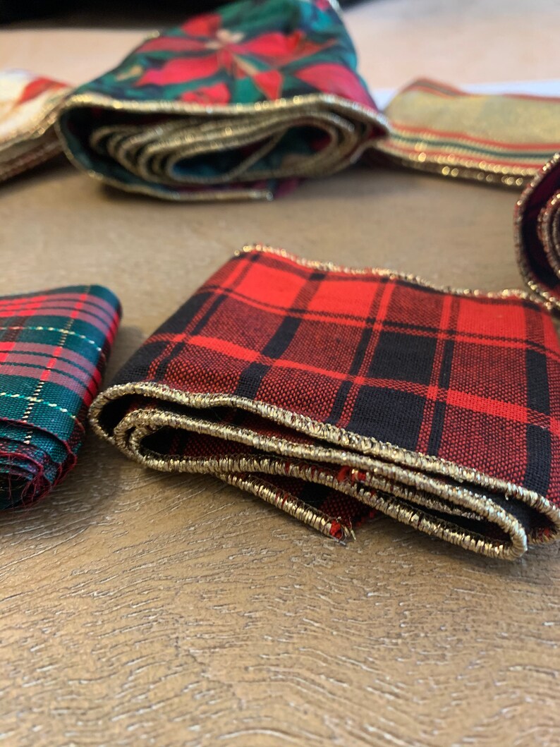 May include: Red and black plaid ribbon with gold trim. The ribbon is folded and has a textured surface.