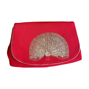 K&ouml;nnte beinhalten: Eine rote Clutch mit einem goldenen gestickten Pfauenmuster.
