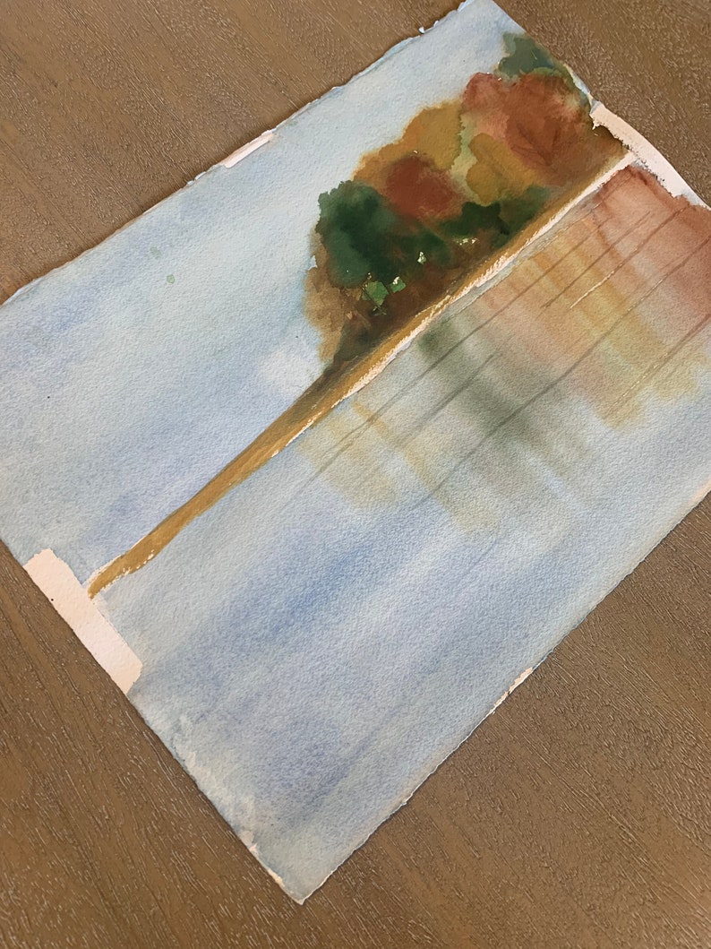 May include: Watercolor painting of a landscape with a tree and water. The tree is painted with shades of green, brown, and yellow. The water is painted with shades of blue and white. The painting is on a white paper.