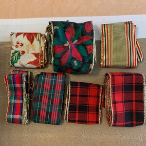 May include: Assortment of seven different Christmas ribbon rolls. The ribbons are red, green, gold, and white with various patterns including plaid, floral, and stripes. The ribbons have gold trim.