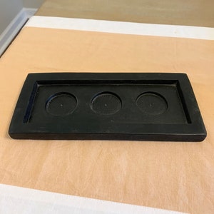 May include: Black wooden tray with three circular cutouts for candles.