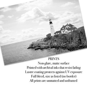 May include: Black and white photograph of a lighthouse on a rocky cliff overlooking the ocean. The lighthouse is tall and white with a black top. The sky is cloudy and the water is choppy. The text "PRINTS" is visible at the bottom of the image, along with a description of the print quality and size.