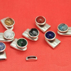 May include: Nine silver-toned metal clasps with different colored gemstone cabochons. The gemstones are: brown, white, green, blue, red, black, blue, and blue.