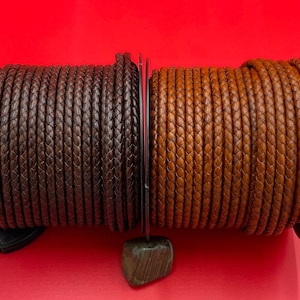 May include: Two spools of braided leather cord. One spool is brown and the other is a lighter brown colour.
