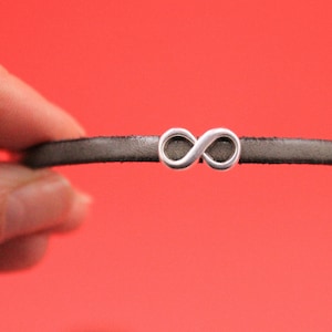 May include: A black leather bracelet with a silver infinity symbol charm.
