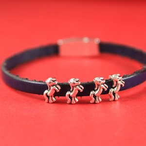 May include: A dark blue leather bracelet with four silver horse charms.