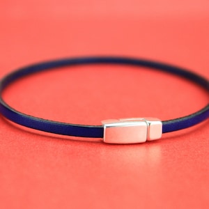 May include: A dark blue leather bracelet with a silver magnetic clasp.
