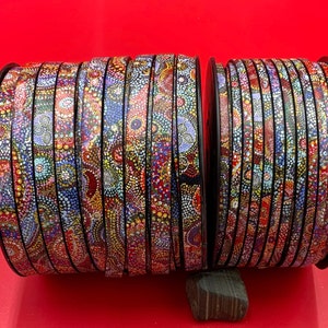 May include: A roll of colorful patterned ribbon with a black background. The ribbon is made of a thin, flexible material and has a variety of colors and designs. The ribbon is perfect for adding a touch of color and style to any project.