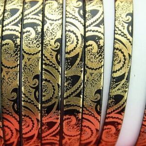 May include: Black leather cord with a gold paisley pattern. The cord is about 1/2 inch wide and is shown in a close-up.