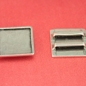 May include: Two silver-toned metal trays, one with a square shape and a smooth surface, and the other with a rectangular shape and two raised bars.