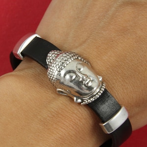 May include: A black leather bracelet with a silver Buddha head charm. The bracelet has a silver clasp.