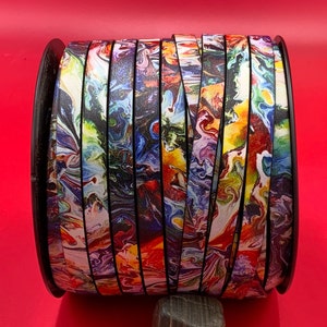 May include: A roll of colorful, multi-colored, abstract patterned leather cord. The cord is black with swirls of red, yellow, blue, and white.