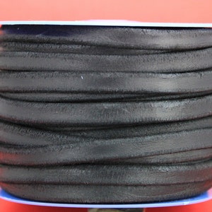 May include: A spool of black leather cord, wound tightly and ready for crafting projects.