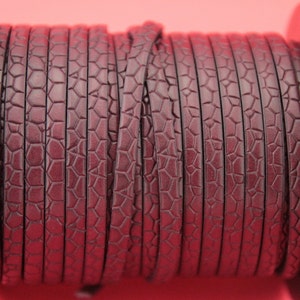 May include: A spool of dark burgundy leather cord with a textured, embossed pattern. The cord is wound tightly around a black spool.