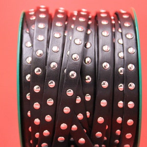 May include: A roll of black leather trim with silver studs. The trim is rolled up and the studs are visible on the surface.
