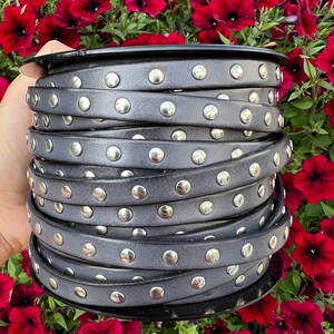 May include: A spool of gray leather trim with silver studs. The trim is rolled up and has a black plastic spool.