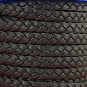 May include: Black braided leather cord, close-up of the texture. The cord is tightly woven and has a smooth, polished finish.