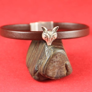 May include: A brown leather bracelet with a silver fox head charm.