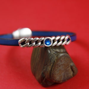 May include: A blue leather bracelet with a silver chain and a blue gemstone accent.