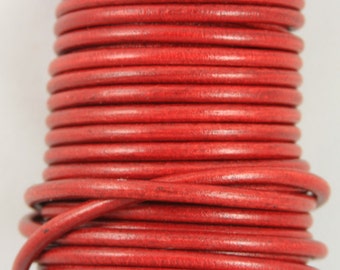 May include: Close-up of a reel of red leather cord. The cord is tightly wound and has a smooth, polished finish.