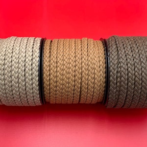May include: Three spools of braided cord in beige, brown, and dark brown. The cord is woven in a herringbone pattern.