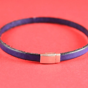May include: A purple leather bracelet with a silver clasp.