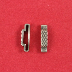 May include: Two silver metal connector pieces for jewelry making. One piece is smooth and the other has a textured surface.