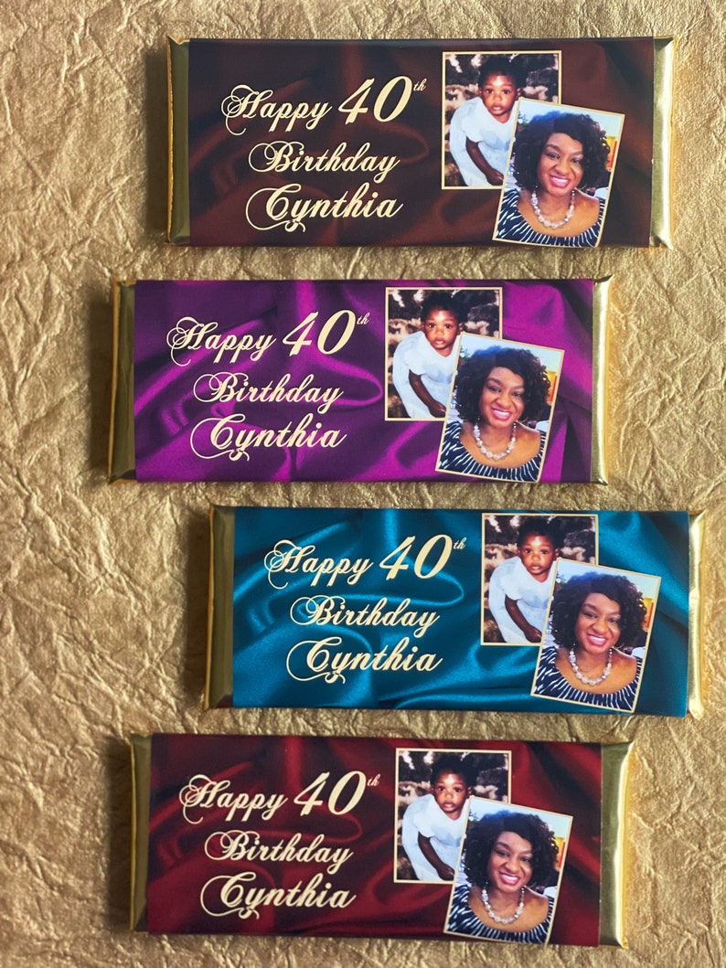 Puede incluir: Cuatro envoltorios de barritas de chocolate con detalles en l&aacute;mina dorada. Cada envoltorio presenta un fondo de color diferente con textura satinada. Los envoltorios tienen el texto "Happy 40th Birthday Cynthia" y una foto de una mujer y un ni&ntilde;o.