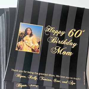 May include: A black and white striped card with gold lettering that says "Happy 60th Birthday Mom". A photo of a woman is in the top left corner. The card also includes the text "Thank you for being the greatest Mom. We love you so much! Bryan, Rolly, Tomiwa, Simi, and Ayo. Bryan, Nory."