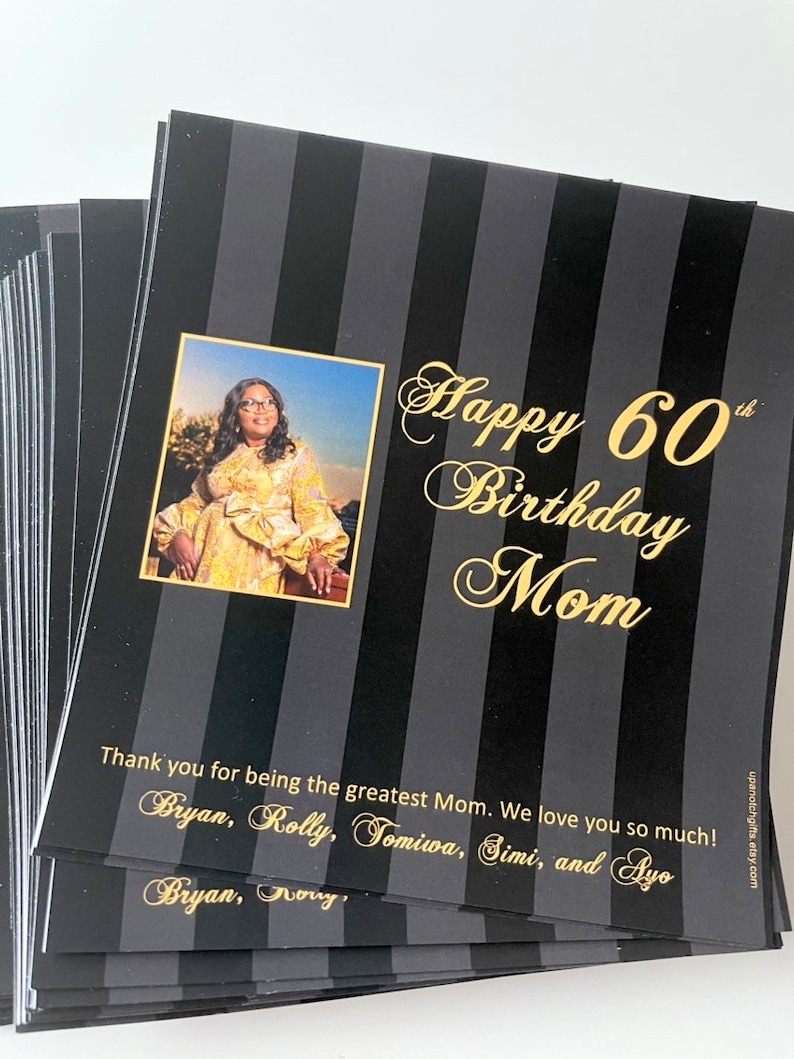 May include: A black and white striped card with gold lettering that says "Happy 60th Birthday Mom". A photo of a woman is in the top left corner. The card also includes the text "Thank you for being the greatest Mom. We love you so much! Bryan, Rolly, Tomiwa, Simi, and Ayo. Bryan, Nory."