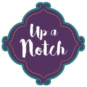 May include: A decorative purple and teal emblem with the words "Up a Notch" in white script. The emblem has a scalloped edge with gold dots and a teal border, set against a white background.