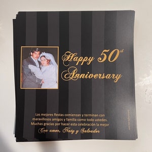 May include: A black and white striped card with gold lettering that says "Happy 50th Anniversary". A photo of a couple in their wedding attire is in the upper left corner of the card. The text below the greeting says "Las mejores fiestas comienzan y terminan con maravillosos amigos y familia como todo ustedes. Muchas gracias por hacer esta celebraci&oacute;n la mejor Con amor, Naty y Salvador"
