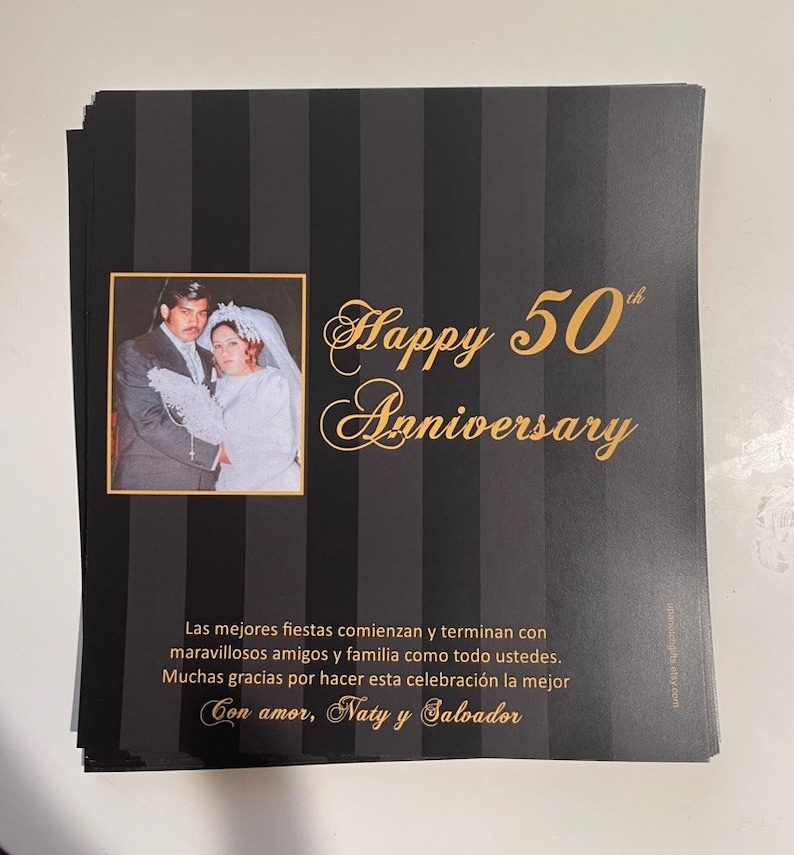 May include: A black and white striped card with gold lettering that says "Happy 50th Anniversary". A photo of a couple in their wedding attire is in the upper left corner of the card. The text below the greeting says "Las mejores fiestas comienzan y terminan con maravillosos amigos y familia como todo ustedes. Muchas gracias por hacer esta celebraci&oacute;n la mejor Con amor, Naty y Salvador"