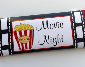 May include: A red, white, and black chocolate bar wrapper with a film strip design. The wrapper has a picture of a bucket of popcorn and the text "Movie Night".