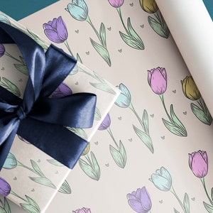 May include: A gift wrapped in beige wrapping paper with a blue ribbon. The wrapping paper has a pattern of colorful tulips.