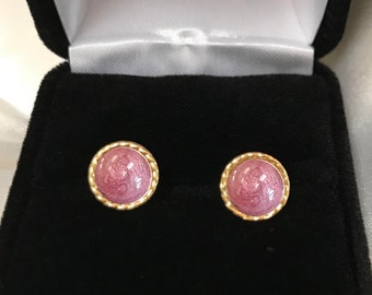 May include: A pair of pink and gold stud earrings in a black velvet box. The box has the words "HEAVEN STONES" printed on the bottom.