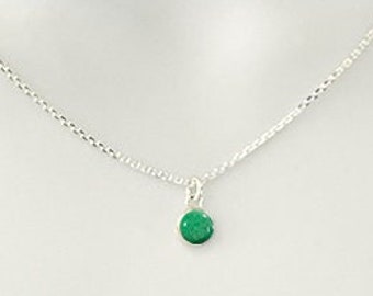 May include: A silver chain necklace with a small emerald green gemstone pendant. The necklace is 6mm wide and is made of sterling silver. The text "HEAVEN STONES® from Memorial Silver" is at the top of the image. The text "6mm Sterling Silver" is at the bottom left of the image. The text "Heaven Stone Color: EMERALD" is at the bottom right of the image.