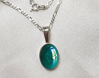 May include: A silver chain necklace with a pendant featuring a green oval-shaped stone.
