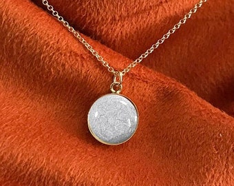 May include: A gold chain necklace with a round pendant featuring a white, sparkly, textured surface. The pendant is inscribed with the words "Heaven Stones® from MEMORIAL SILVER".