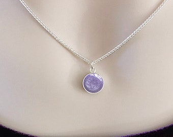 May include: A silver chain necklace with a small round pendant. The pendant is made of silver and has a purple, speckled, stone-like material inside. The text "HEAVEN STONES® from Memorial Silver" is at the top of the image.