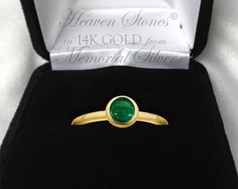 May include: A gold ring with a green gemstone set in a bezel setting. The ring is in a black velvet box with the text "Heaven Stones® in 14K GOLD from Memorial Silver".