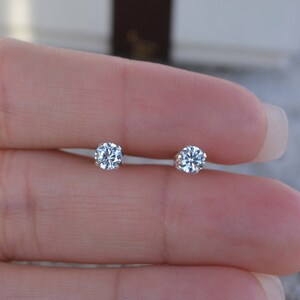May include: A pair of small, round, clear diamond stud earrings.